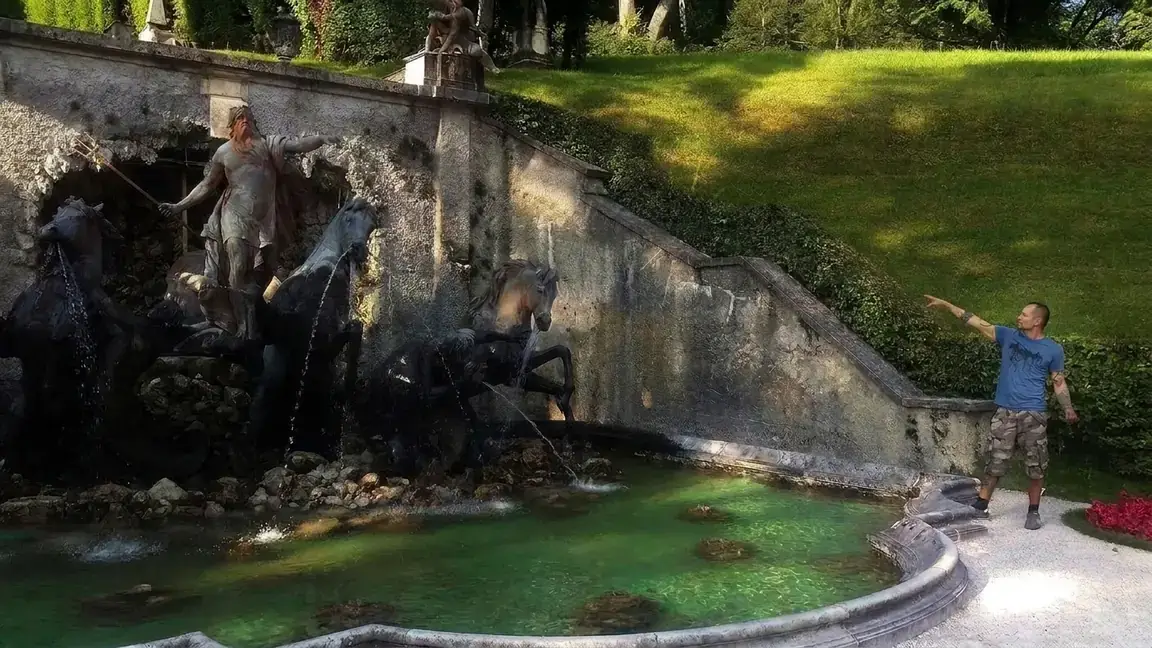 Yanni Sanmiguel pointing at the statue of Poseidon in a fountain, both charged with energy